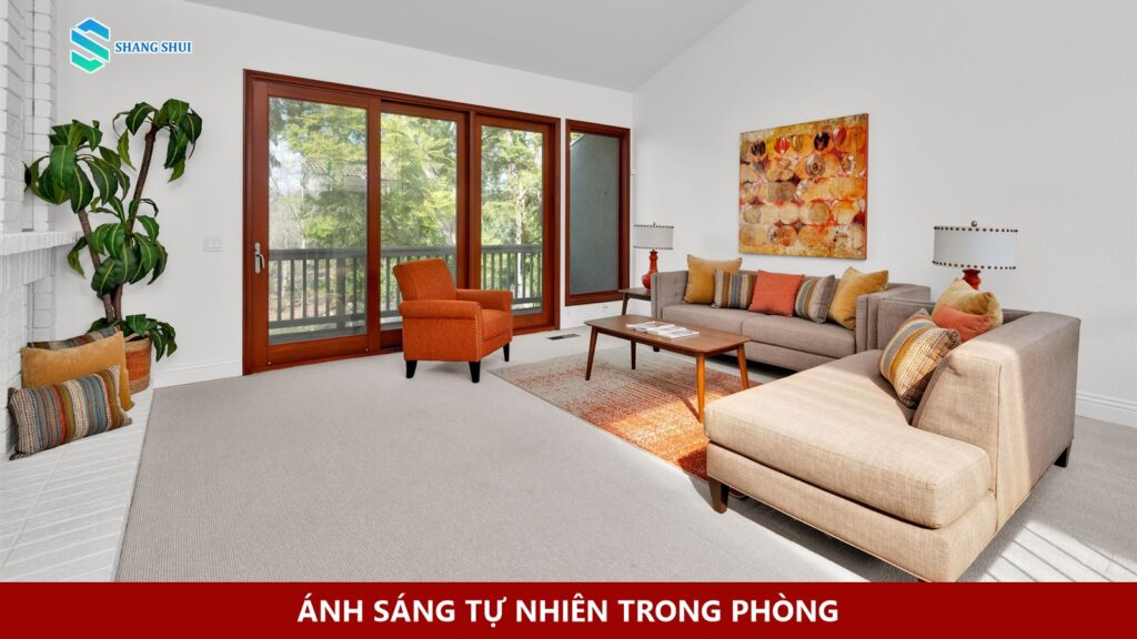 Phòng khách với cửa kính lớn, ghế sofa và vệt nắng trên sàn.