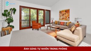 Phòng khách với cửa kính lớn, ghế sofa và vệt nắng trên sàn.