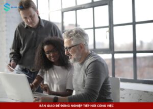 Nhóm đồng nghiệp trao đổi tài liệu bên laptop khi bàn giao công việc cuối ca