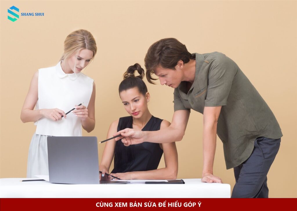Ba đồng nghiệp xem laptop và trao đổi góp ý trong công việc
