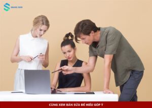 Ba đồng nghiệp xem laptop và trao đổi góp ý trong công việc