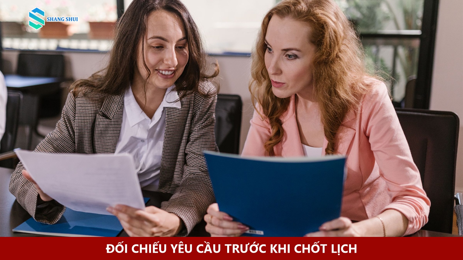 Hai người cùng xem tài liệu và tập hồ sơ tại bàn.