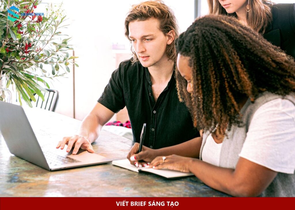Hai người trao đổi công việc bên laptop và sổ ghi chép
