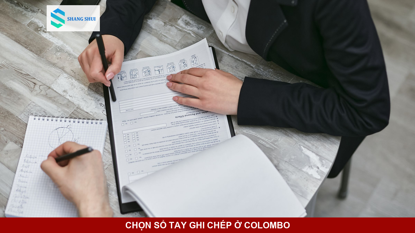 Các cuốn sổ tay bìa cứng và giấy thủ công đặt ngay ngắn trên bàn làm việc.